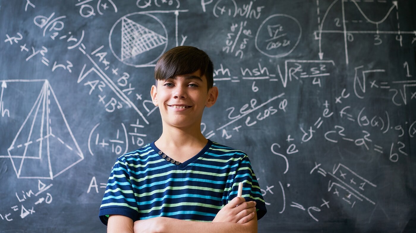 Smart boy in front of blackboard with equations