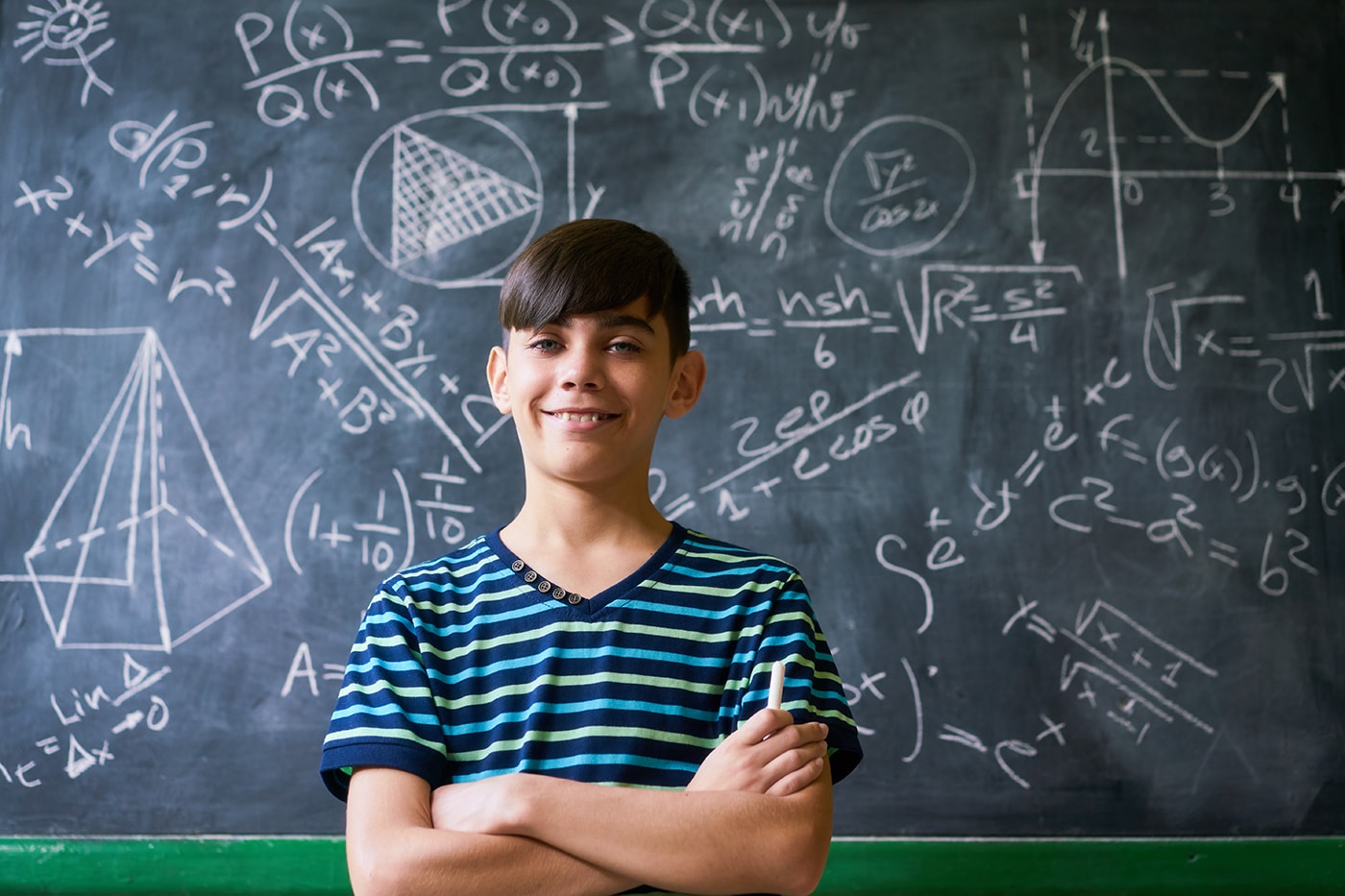Smart boy in front of blackboard with equations