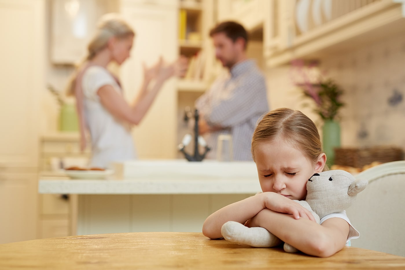 Worried child with parents arguing in background