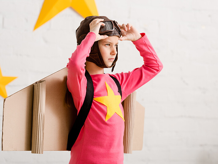 Confident child with cardboard wings touching goggles